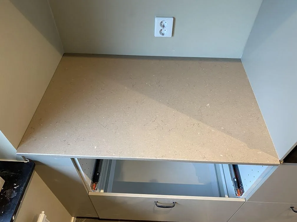 Separat bänksektion i polerad Silestone Coral Clay komposit med tunn framkant och ljus stenstruktur i ett kök i Malmö.