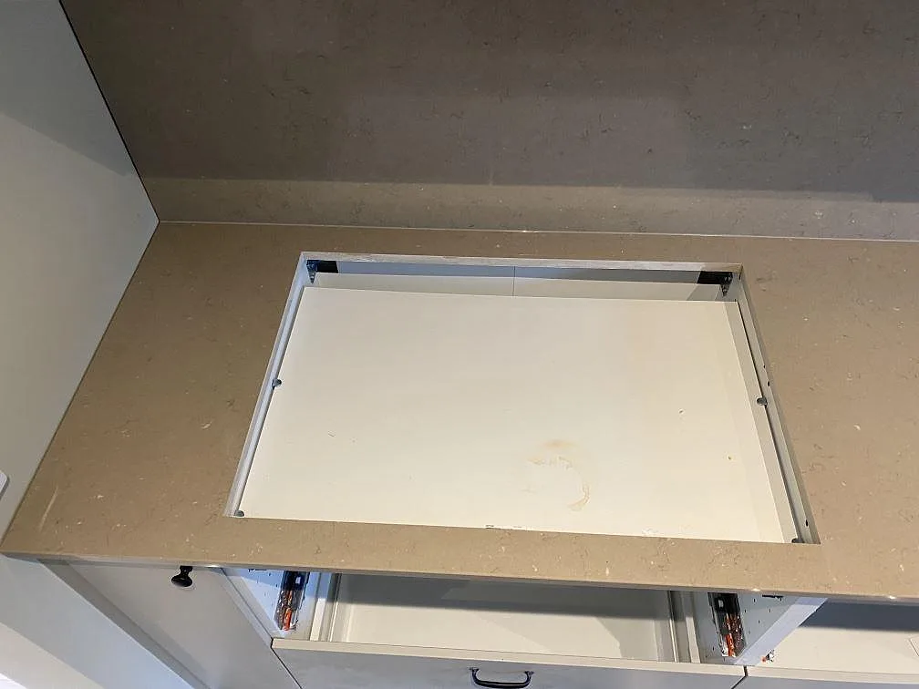 Detalj av hällöppning i polerad Silestone Coral Clay köksbänkskiva med stänkvägg bakom arbetsytan i Malmö.