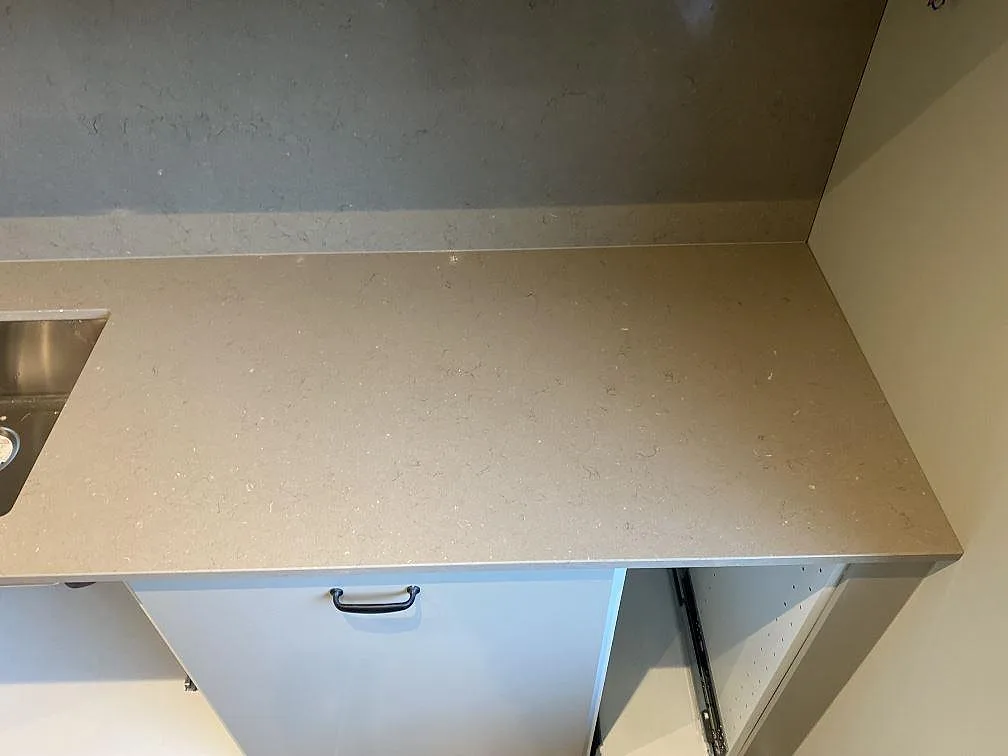 Sidoyta i polerad Silestone Coral Clay komposit vid rostfri diskho och stänkvägg, monterad på ljusa köksstommar i Malmö.