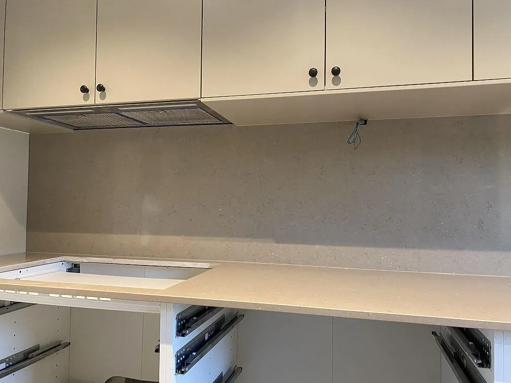 Lång köksbänkskiva i polerad Silestone Coral Clay komposit med hällöppning och stänkvägg under överskåp i Malmö.