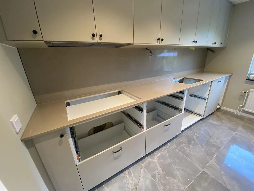 Köksbänkskiva i polerad Silestone Coral Clay komposit med stänkvägg, rostfri diskhozon och hällöppning i ett kök under montering i Malmö.