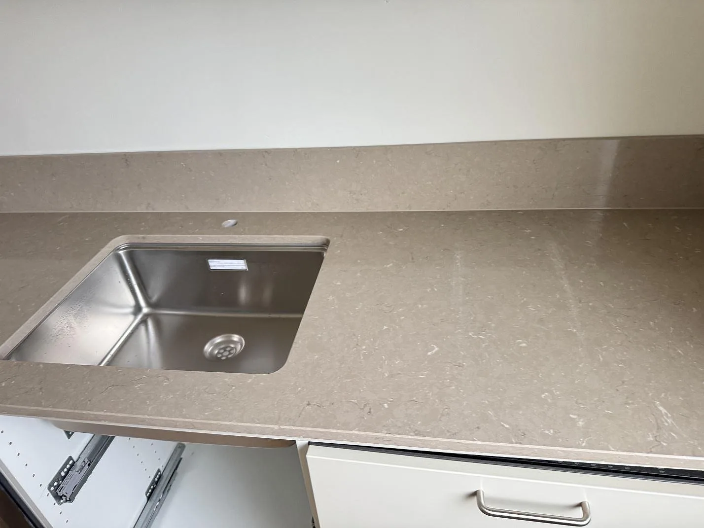 Köksbänkskiva i polerad Silestone Coral Clay med rostfri diskho och låg stänkkant i ett kök i Malmö.