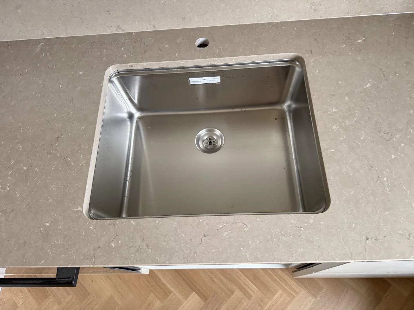 Närbild på rostfri diskho i polerad Silestone Coral Clay med ljus stänkkant i ett kök i Malmö.