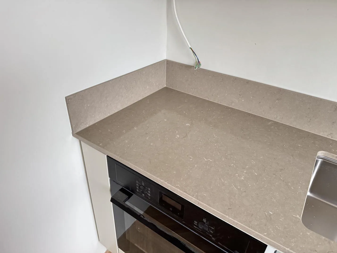 Köksbänkskiva i polerad Silestone Coral Clay med stänkkant och inbyggd ugn under montering i Malmö.