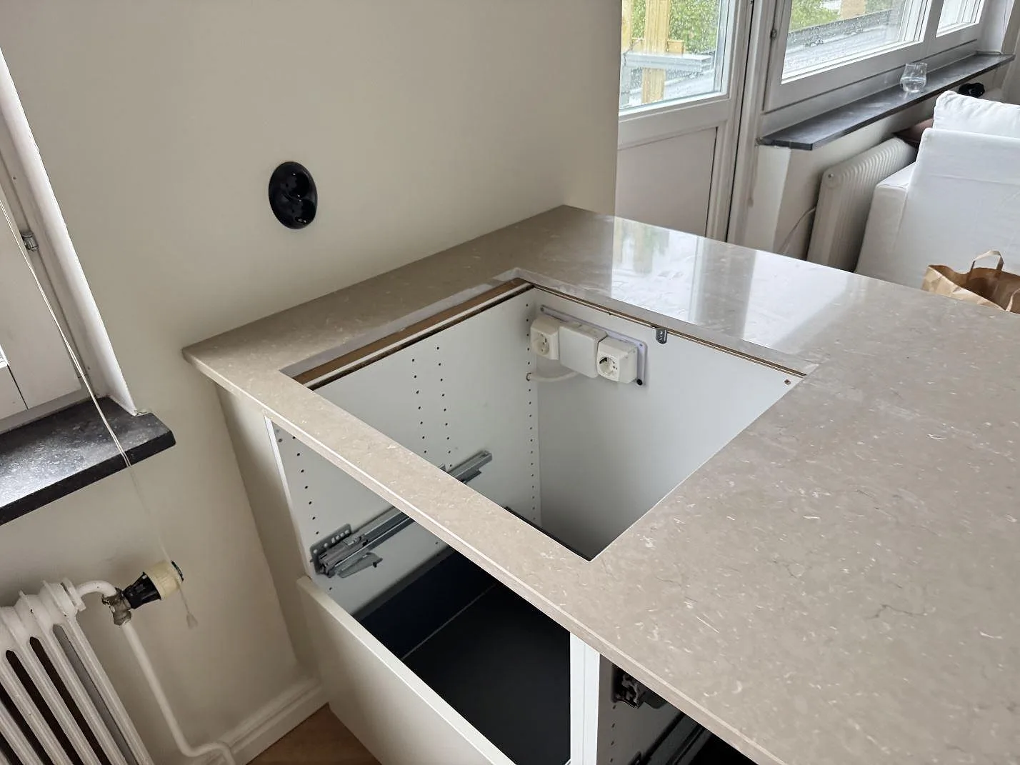Polerad Silestone Coral Clay runt en diskhouskärning vid fönster i ett kök under montering i Malmö.