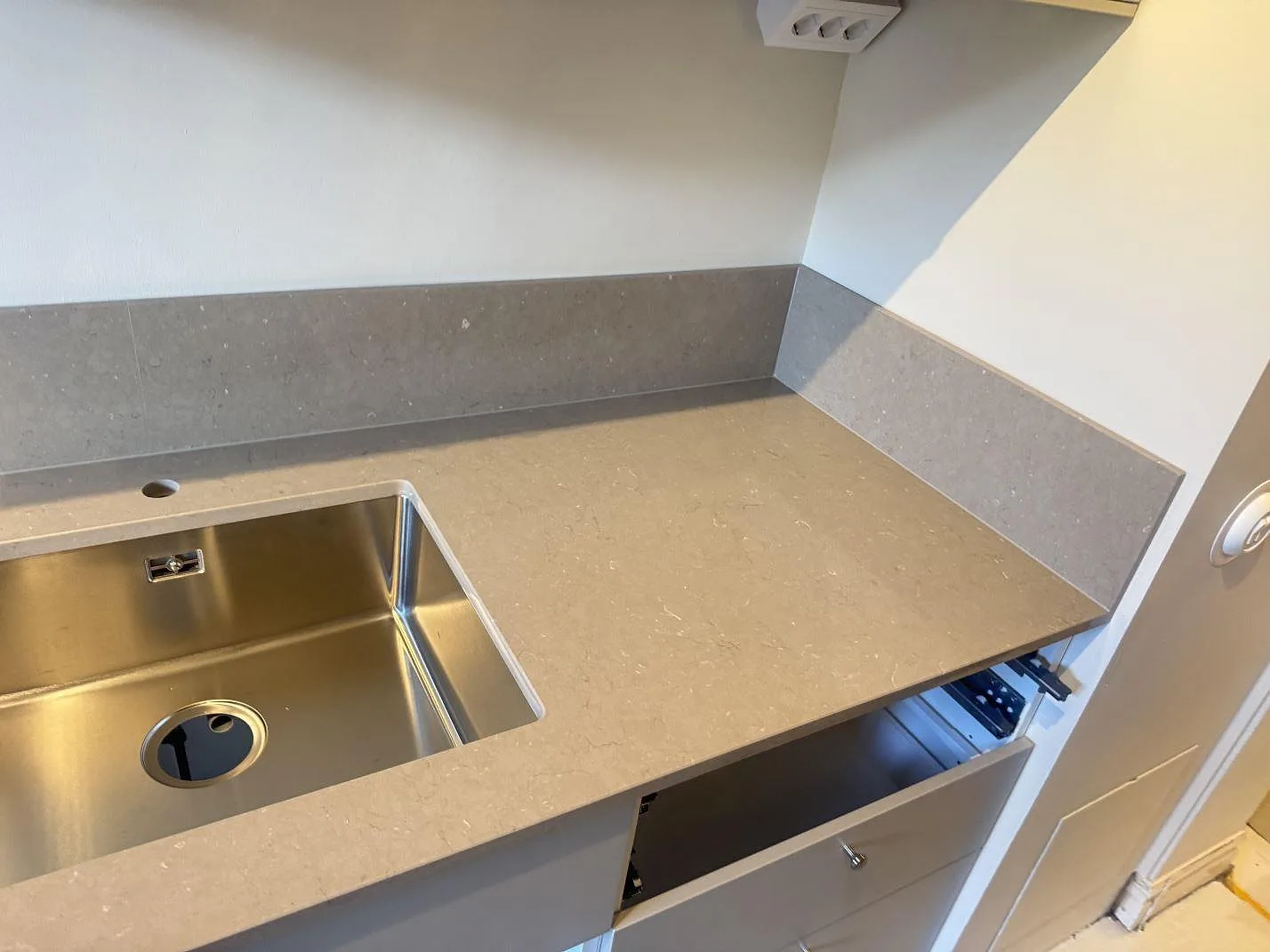 Hörnparti i kök med underlimmad rostfri diskho, polerad Silestone Coral Clay och låg stänkkant i Malmö.