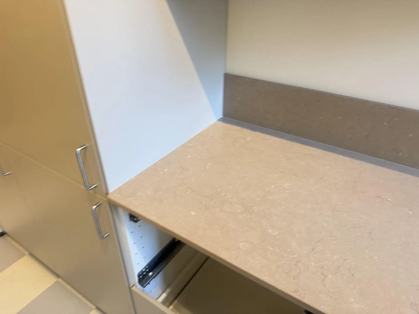 Avslut vid högskåp med polerad Silestone Coral Clay arbetsyta och lågt stänkskydd i ett kök i Malmö.