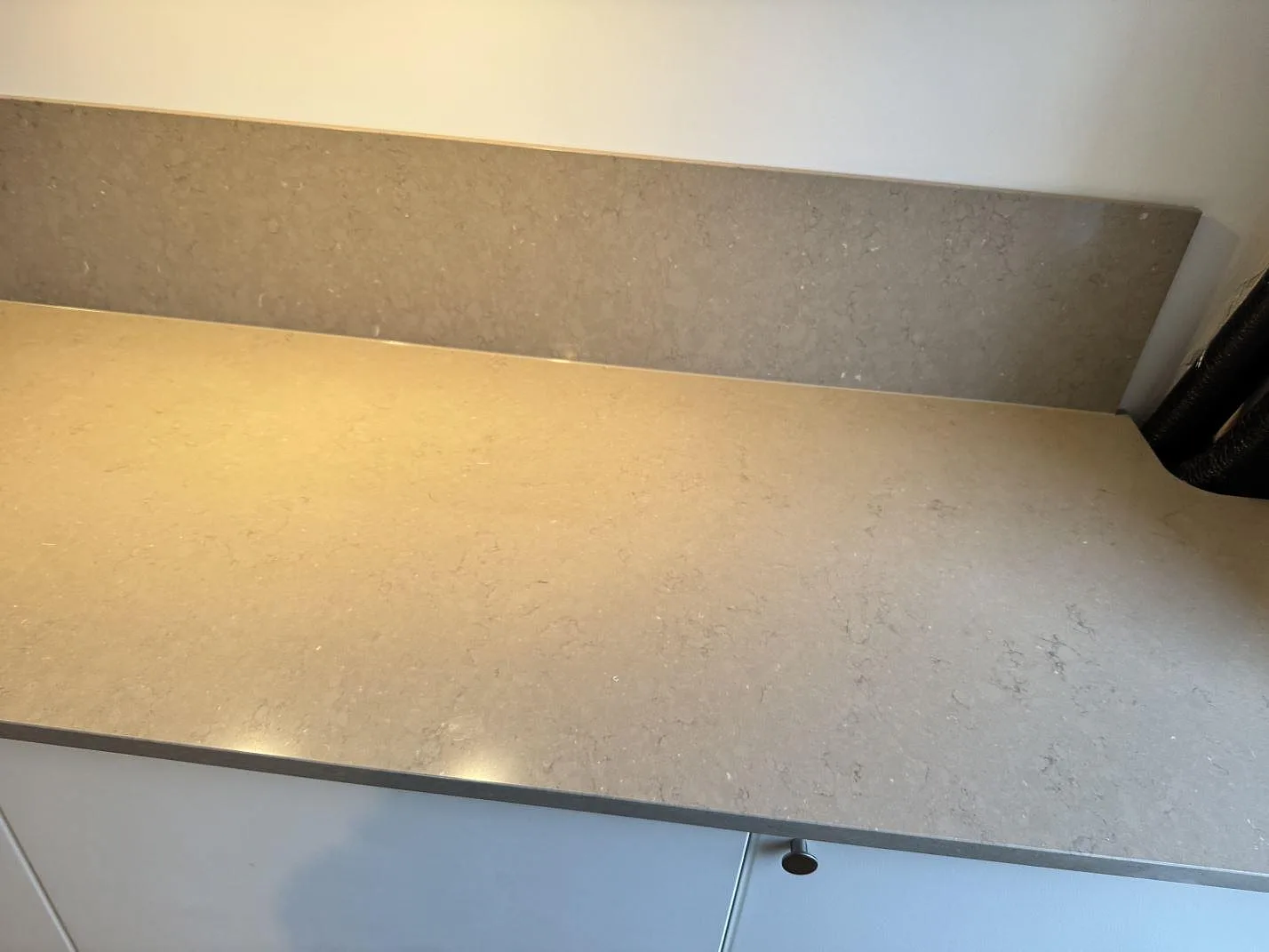 Lång köksbänk i Silestone Coral Clay med lågt uppvikt stänkskydd och polerad yta i ett kök i Malmö.