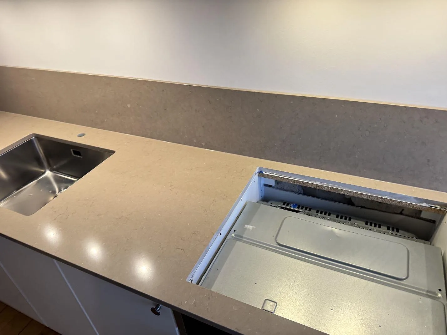 Köksbänkskiva i Silestone Coral Clay, polerad varm greige komposit, med underlimmad rostfri diskho och urtagning för induktionshäll i ett kök i Malmö.