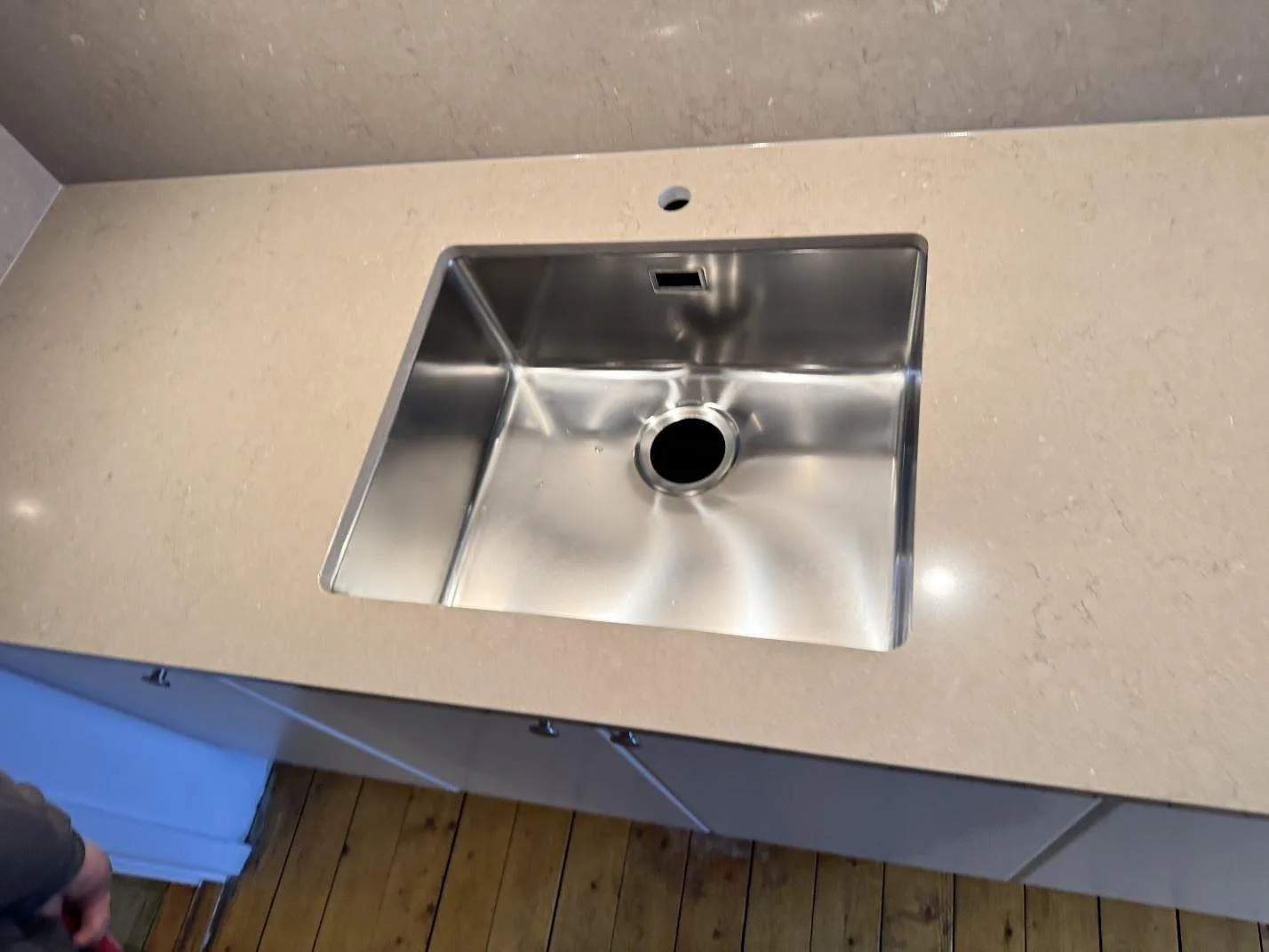 Underlimmad rostfri diskho uppifrån i polerad Silestone Coral Clay bänkskiva med borrat blandarhål i ett kök i Malmö.