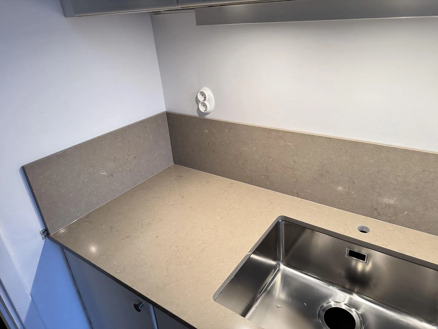 Hörnparti i Silestone Coral Clay med uppvikt polerat stänkskydd och underlimmad rostfri diskho i ett kök i Malmö.