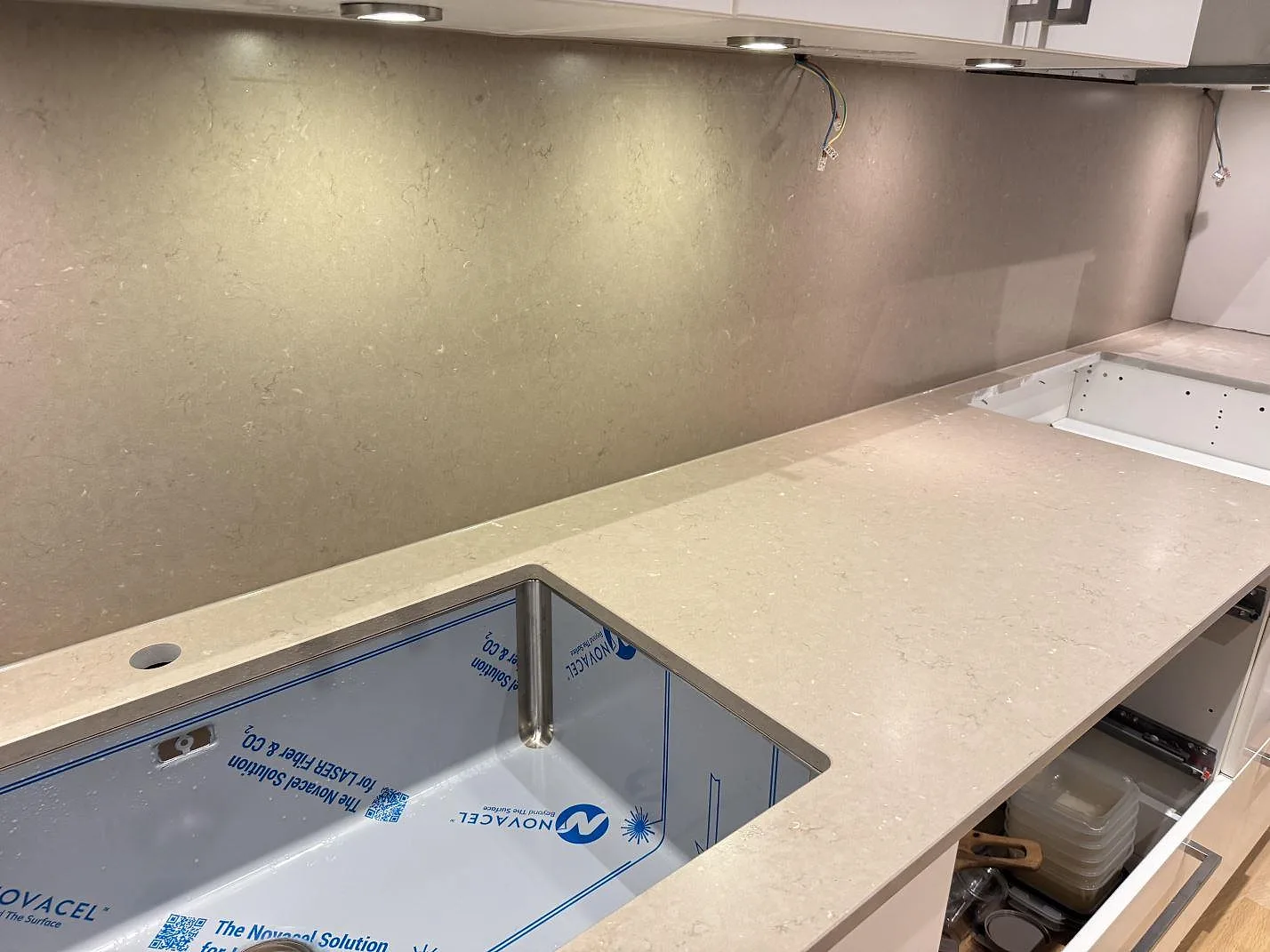 Lång köksbänkskiva i Silestone Coral Clay med stänkskydd i samma sten, underlimmad rostfri diskho och undercentral belysning, mid-install kök i Malmö.