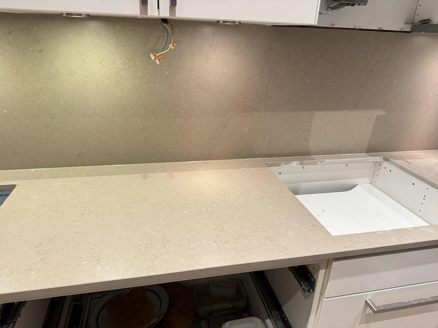 Köksbänkskiva i matt beige Silestone Coral Clay med förberett urtag för vitvaror och stänkskydd i samma sten, kök under montering i Malmö.