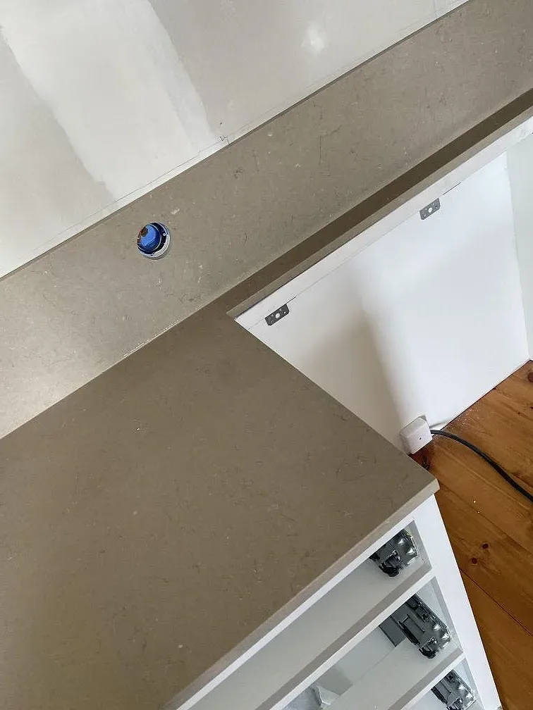 Närbild på polerad greige Silestone Coral Clay bänkskiva med blandarhål och fint spridd ådring i ett kök i Mölltorp.