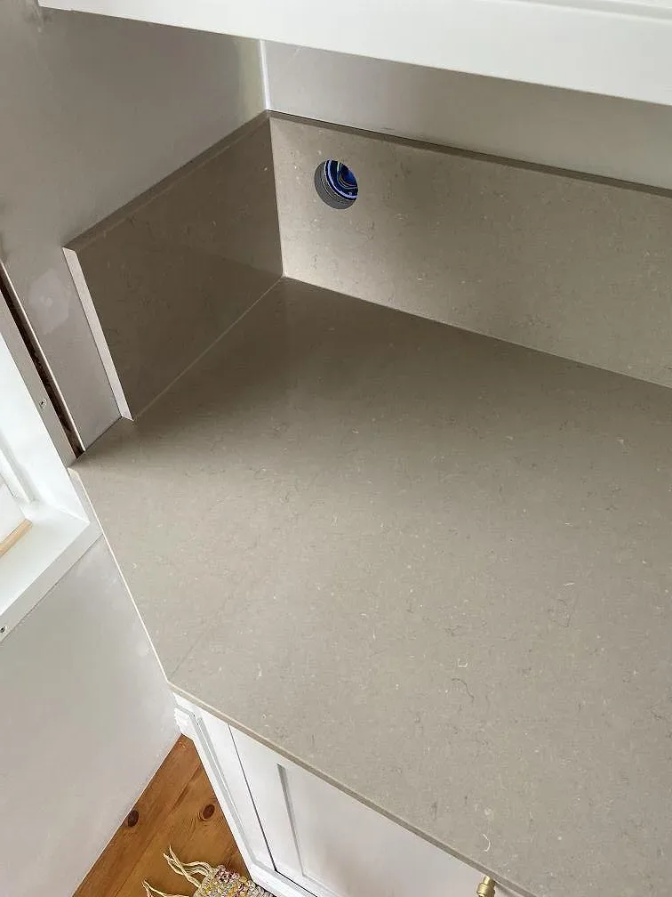 Polerad Silestone Coral Clay köksbänkskiva med stänkkant och blandarhål i den greige kvartskompositytan, Mölltorp.
