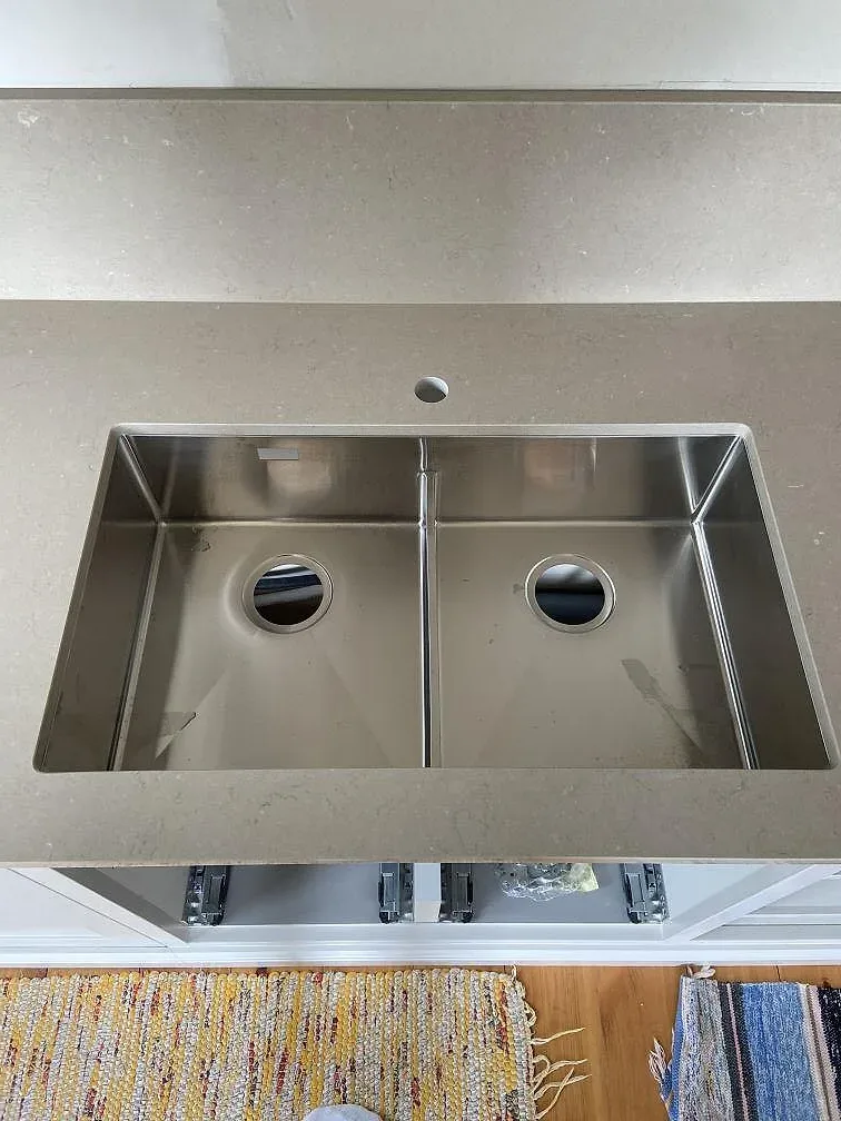Underlimmad rostfri dubbelho under greige Silestone Coral Clay bänkskiva med separat borrat blandarhål i stenen, kök i Mölltorp.