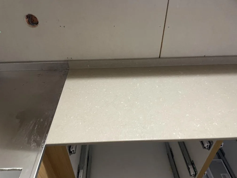Närbild av matt Silestone Coral Clay-bänkskiva med diskret ljus ådring och låg stänkkant under montering i Mölnlycke.