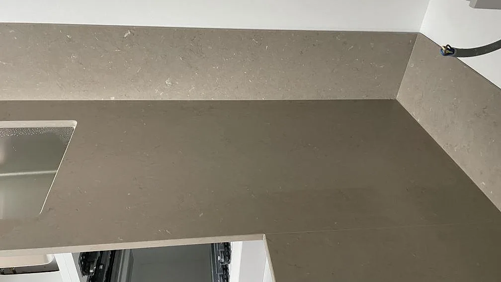 Hörnparti med köksbänkskiva och stänkskydd i Silestone Coral Clay, matt komposit, under montering i Nässjö.