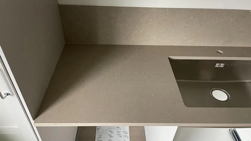 Detalj av köksbänkskiva i Silestone Coral Clay, matt komposit, med rostfri diskho och stänkskydd i ett kök i Nässjö.