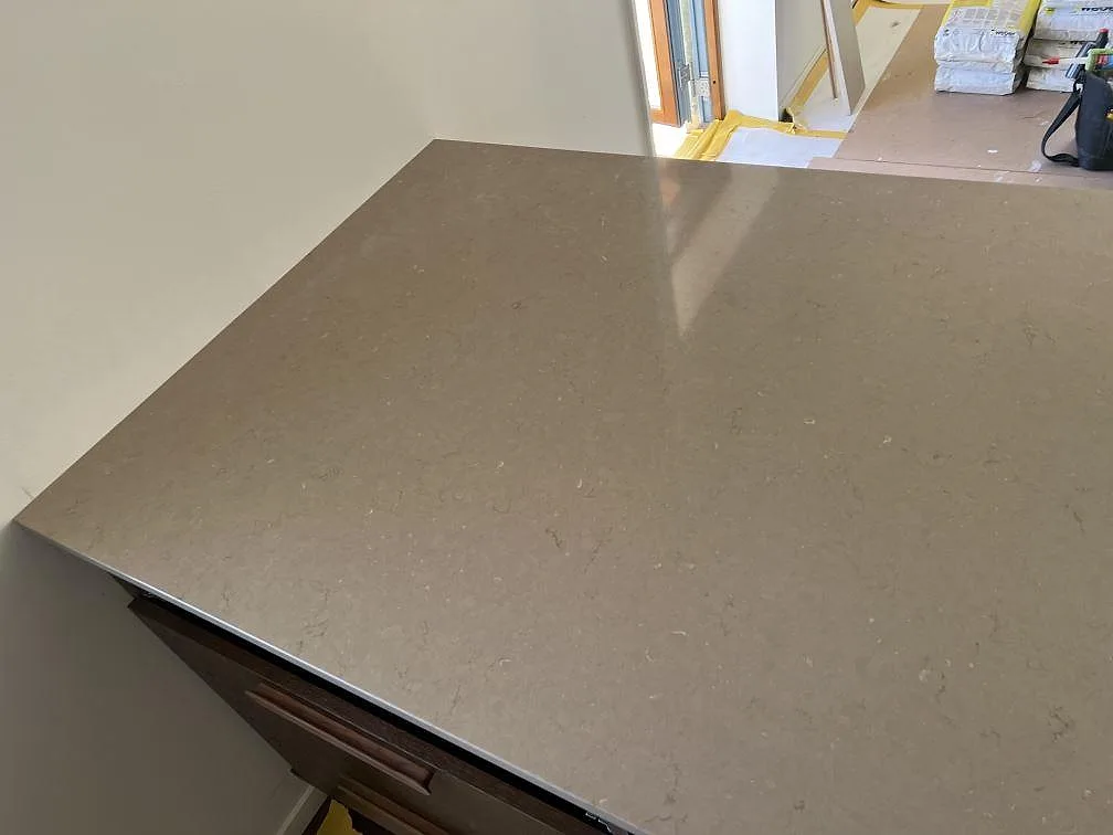 Närbild av köksö i polerad Silestone Coral Clay med mjuk gråbeige komposityta i Nättraby.