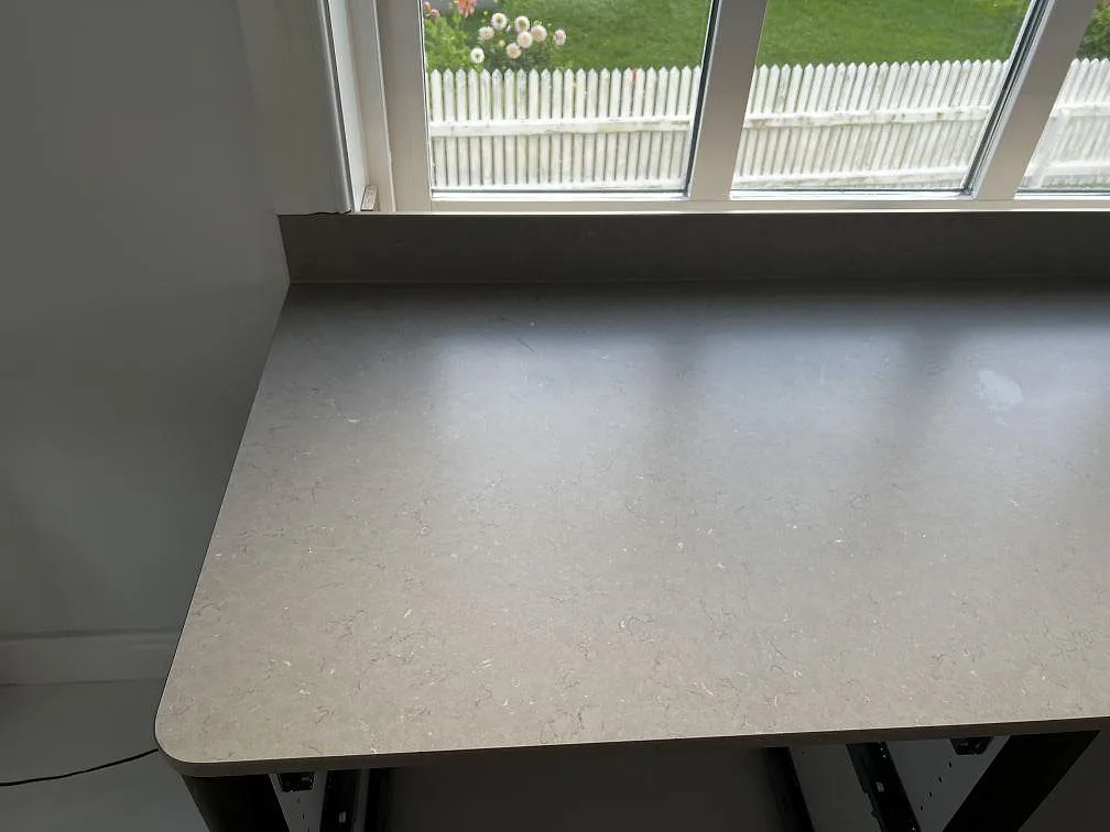 Närbild av rundad kant på matt Silestone Coral Clay bänkskiva med låg stänkkant under fönster i Öckerö.