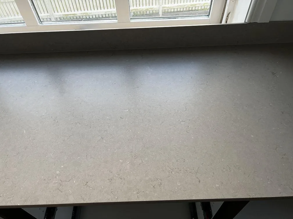 Ytbild av matt Silestone Coral Clay kompositbänkskiva med varm gråbeige struktur vid fönster i Öckerö.