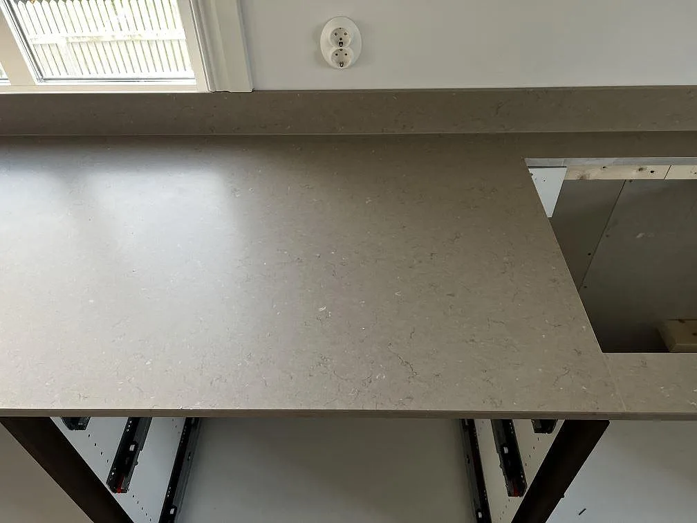 Köksbänkskiva i matt Silestone Coral Clay med uppvikt stänkkant och rektangulär utskärning under montering i Öckerö.