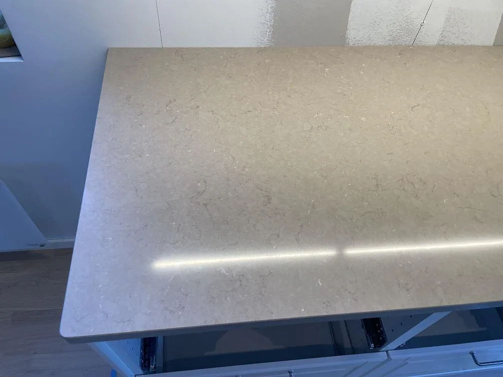 Närbild av polerad Silestone Coral Clay med ljusreflex och diskret teckning på köksbänk i Ösmo.