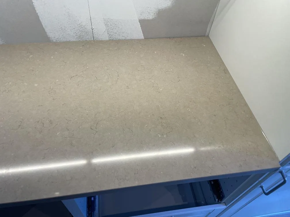 Detalj av hörnyta i polerad Silestone Coral Clay, monterad som köksbänkskiva intill vägg i Ösmo.