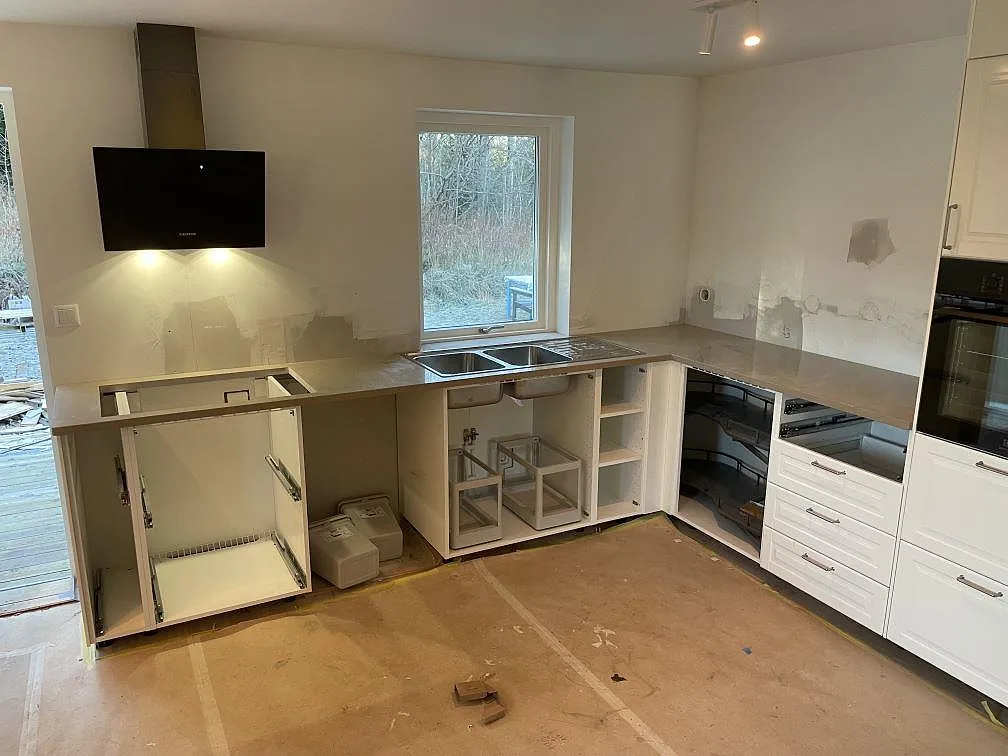 L-formad köksbänkskiva i polerad Silestone Coral Clay, kvartskomposit, under montering i ett kök i Ösmo.