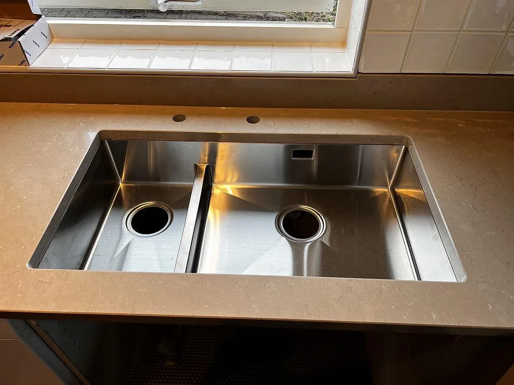 Underlimmad dubbelho i rostfritt stål monterad i polerad Silestone Coral Clay med låg stänkkant i kök i Oxie.