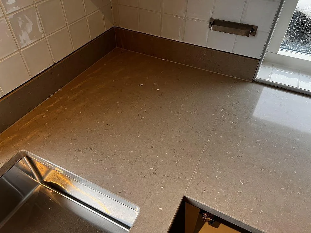Hörnyta i polerad Silestone Coral Clay med uppvikt stänkkant och synlig kvartskompositteckning i Oxie.