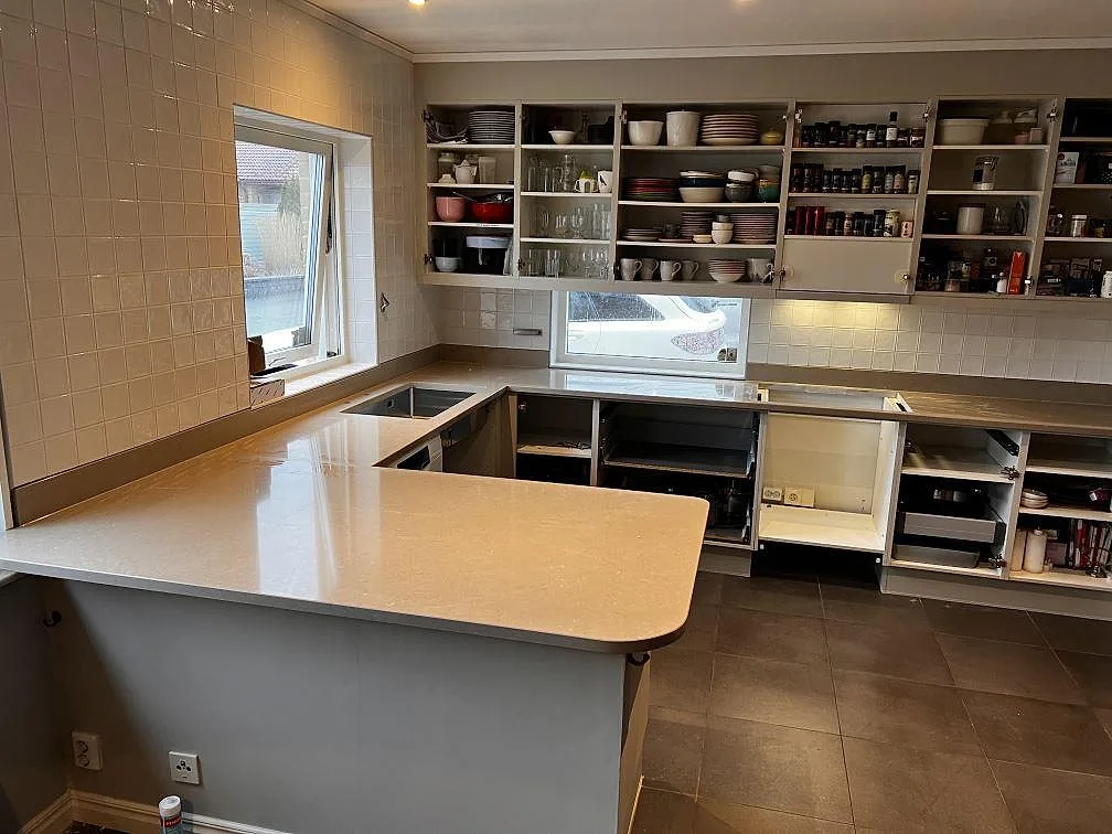 Köksbänkskiva i varm greige Silestone Coral Clay, polerad komposit, med halvö, stänkskydd och underlimmad dubbelho i ett kök i Oxie.