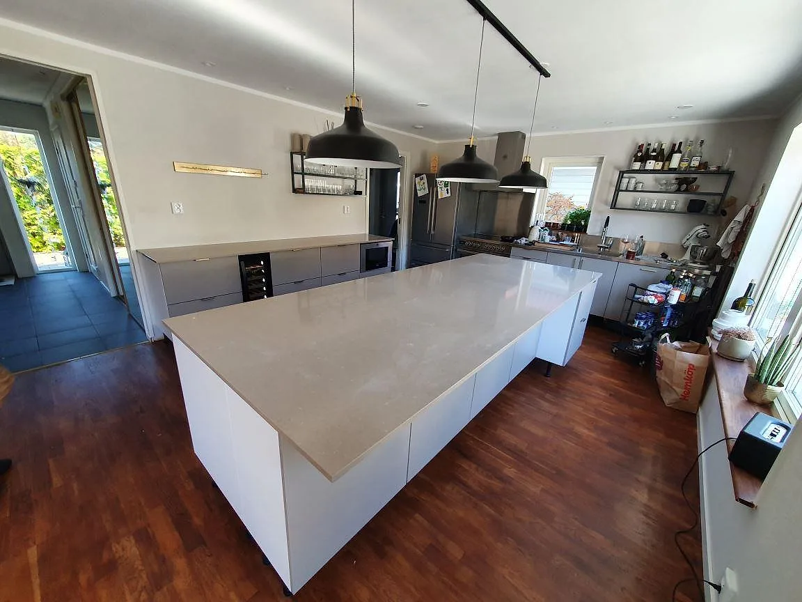 Köksö i polerad Silestone Coral Clay sedd från sidan med den släta bänkytan i fokus i ett kök i Rönninge.