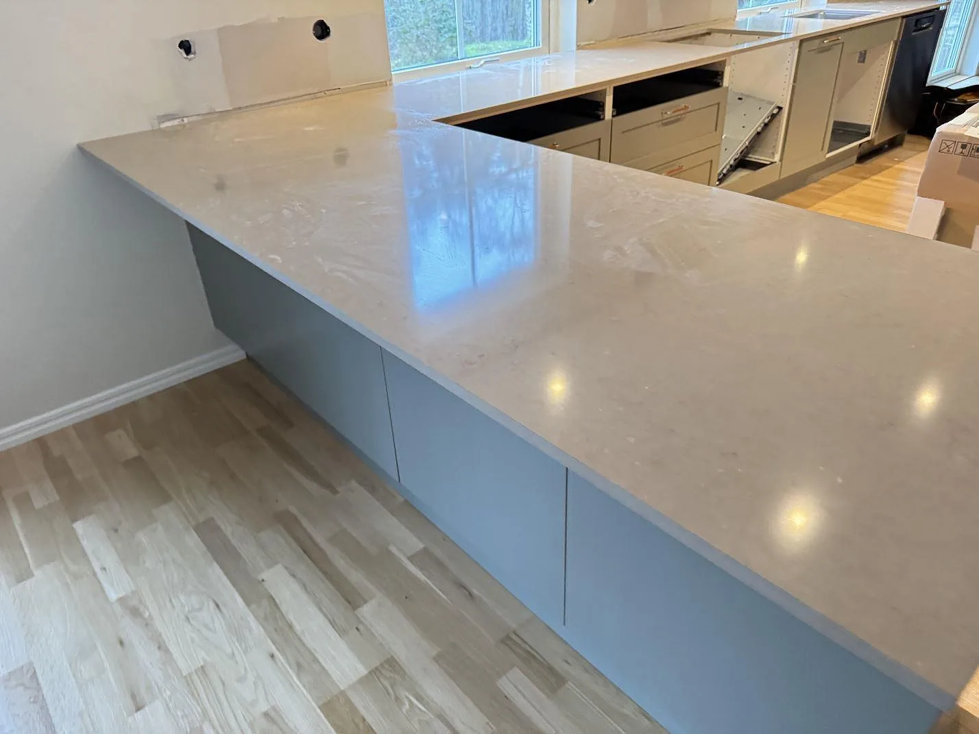 Närbild på polerad Silestone Coral Clay köksbänkskiva med ljus stenstruktur och grå köksstommar i Saxtorp.
