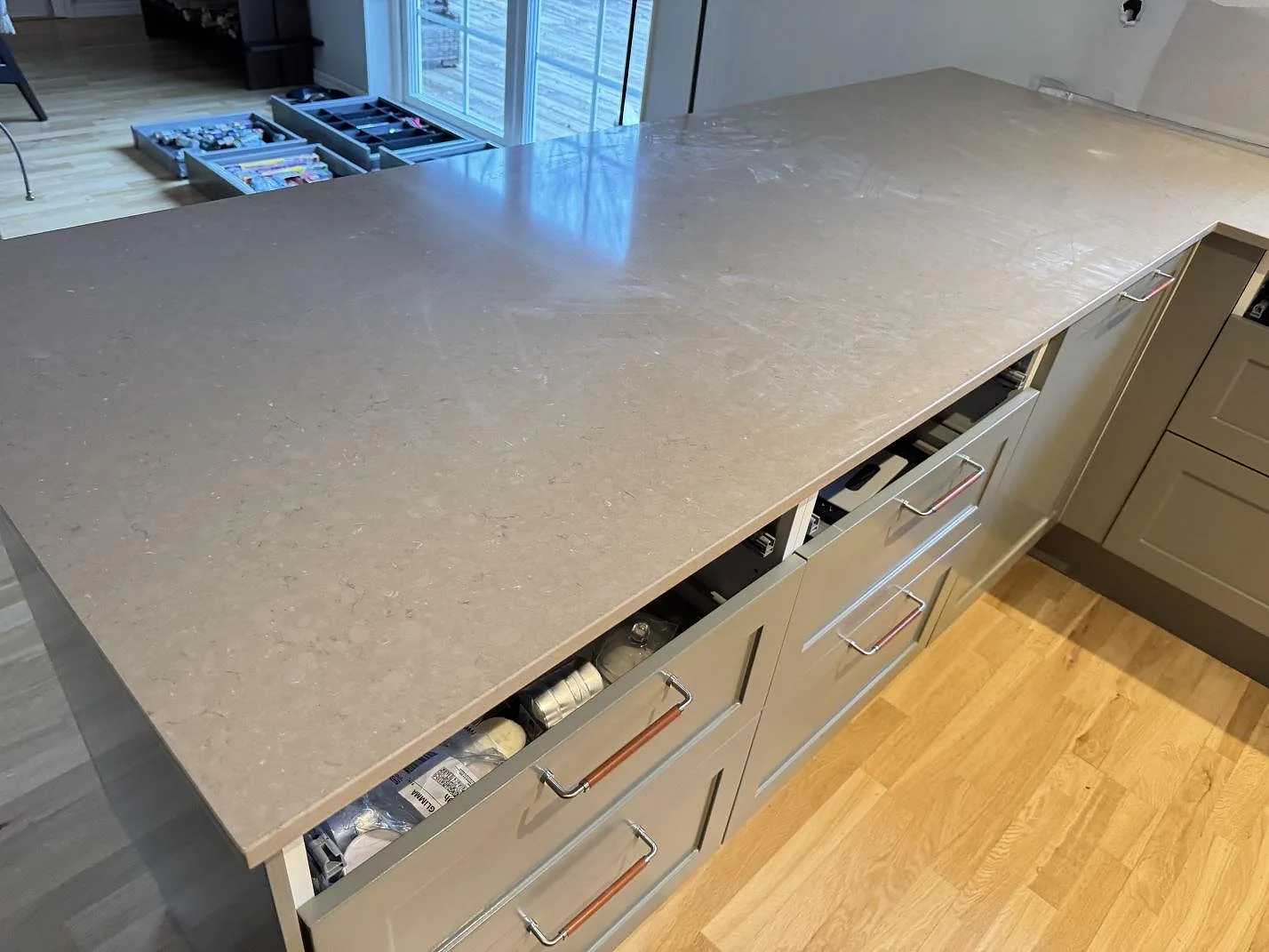 Detalj av Silestone Coral Clay arbetsyta i polerad komposit över öppna lådor under köksmontering i Saxtorp.