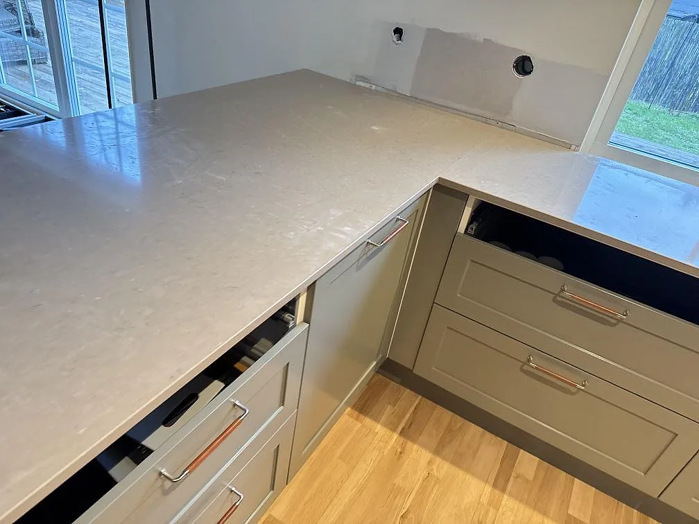 Polerad Silestone Coral Clay bänkskiva runt hörn i kök med synliga luckor och öppen förvaring i Saxtorp.