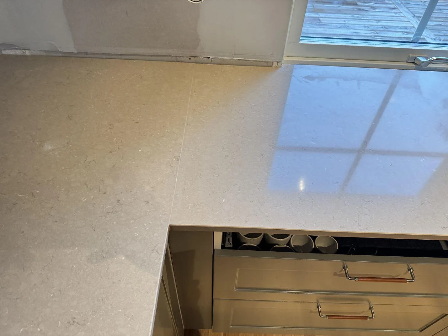 Ytbild av Silestone Coral Clay köksbänkskiva, polerad komposit, med fönsterreflexer och monteringsdetaljer i Saxtorp.