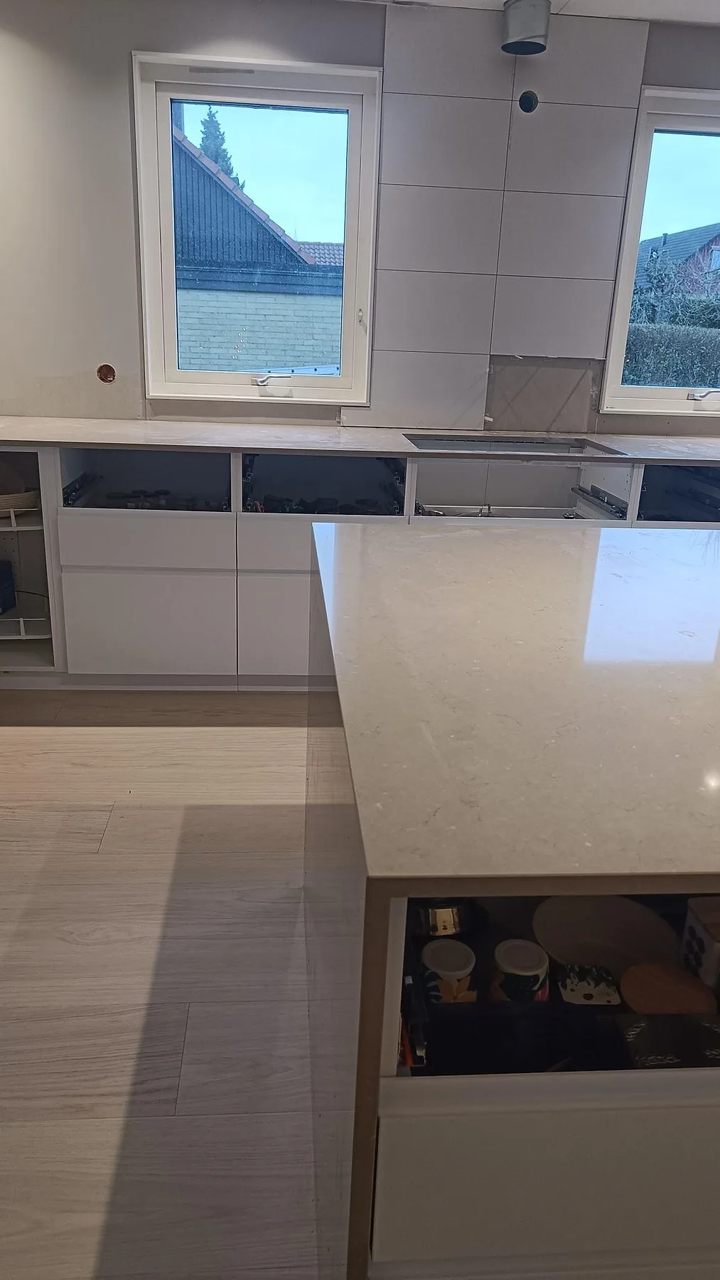 Polerad Silestone Coral Clay som köksö och bänkskiva under fönster i ett kök i Sjöbo.