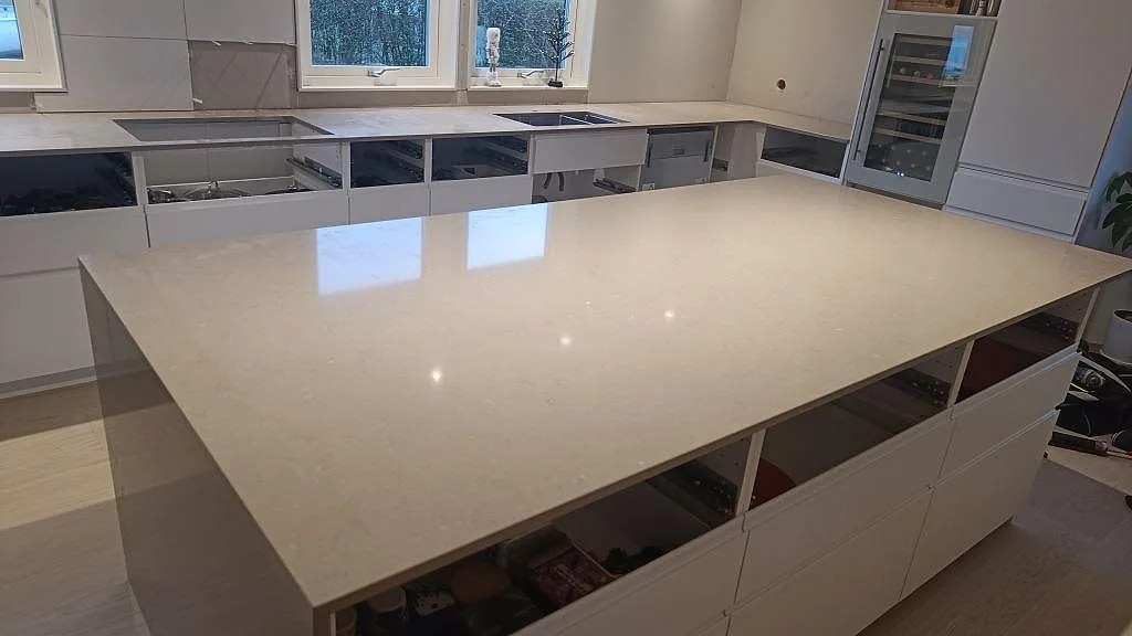 Stor köksö med polerad Silestone Coral Clay i ljus kvartskomposit och väggmonterade bänkskivor i kök i Sjöbo.
