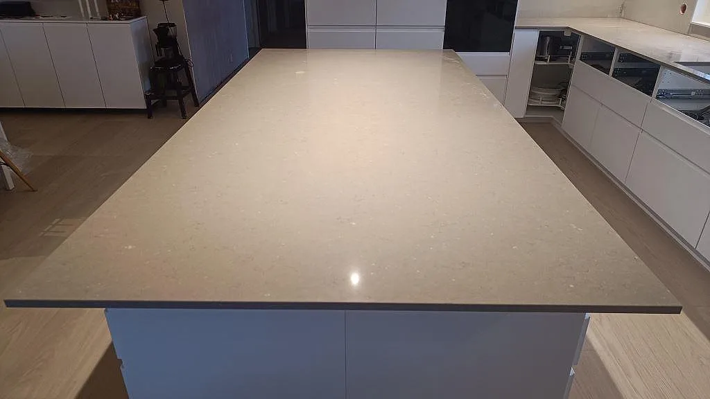 Närbild från köksön med polerad Silestone Coral Clay, 20 mm kvartskomposit, i kök under montering i Sjöbo.