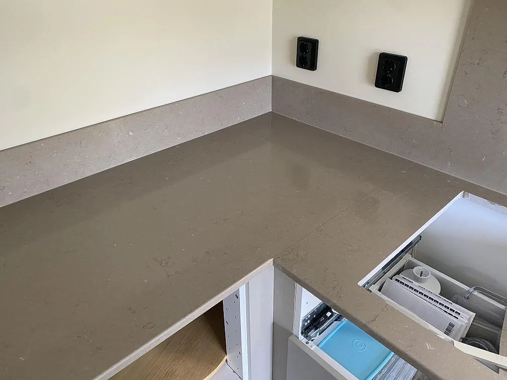 Köksbänkskiva i Silestone Coral Clay med uppvikt stänkkant i hörnet, polerad greige kvartskomposit i ett kök i Skanör.