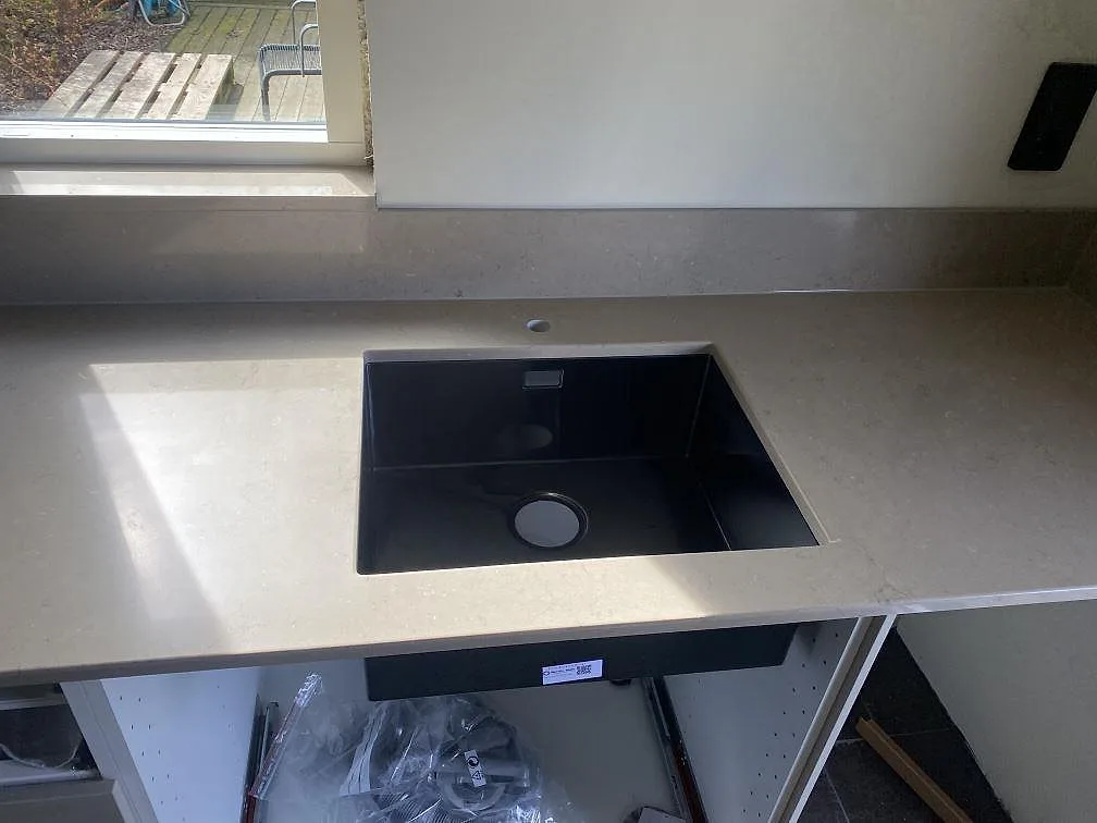 Underlimmad svart kompositdiskho i polerad Silestone Coral Clay köksbänkskiva med förborrat blandarhål och uppvikt stänkkant i Skanör.