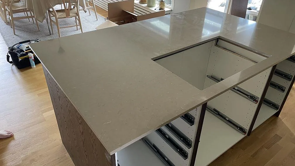 Närbild av köksö i polerad Silestone Coral Clay med hällöppning och synlig stenprofil under montering i Skanör.