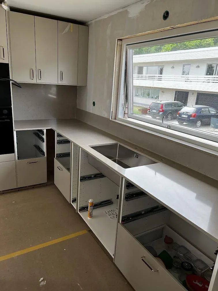 Lång bänkrad i polerad Silestone Coral Clay med underlimmad rostfri diskho och fönsterläge i ett kök i Skövde.