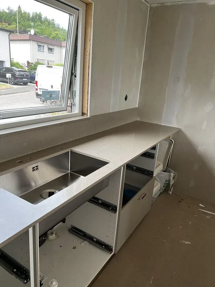 Diskbänksdel i polerad Silestone Coral Clay med underlimmad rostfri diskho vid fönstret i ett kök i Skövde.