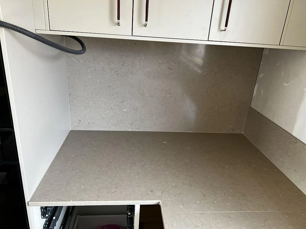 Polerad Silestone Coral Clay som bänkskiva och 12 mm stänkskydd under väggskåp i ett kök i Skövde.