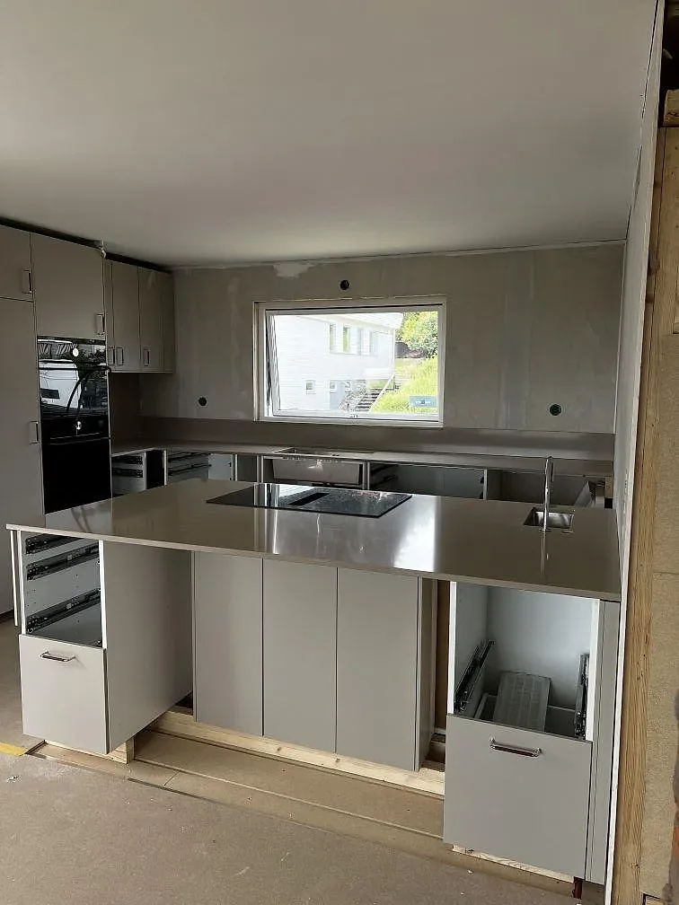 Köksbänkskiva i polerad Silestone Coral Clay med svart induktionshäll, rostfri diskho och vitt U-kök under montering i Skövde.
