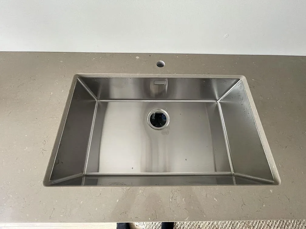 Underlimmad rostfri enkelho i polerad Silestone Coral Clay köksbänkskiva i ett kök i Skogås.