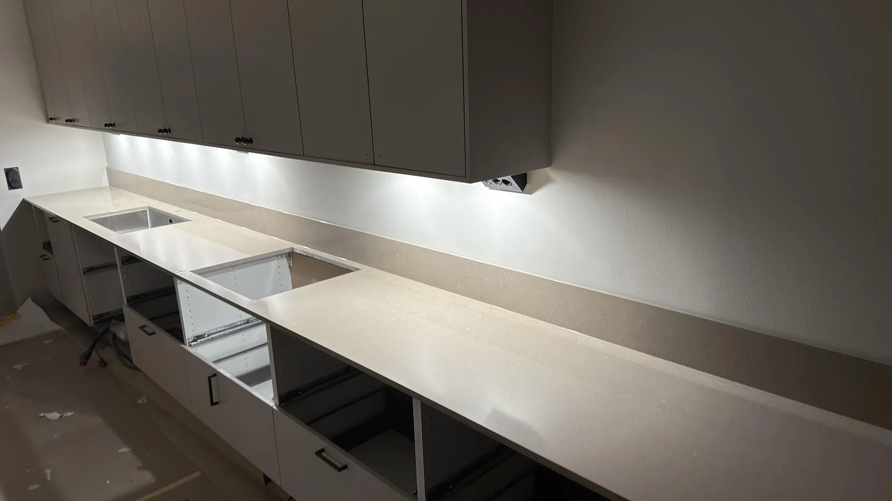 Underlimmad rostfri diskho infälld i en polerad bänkskiva i beige Silestone Coral Clay i ett kök i Skogås.